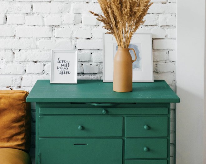 Green drawers cabinet with a vase on top 